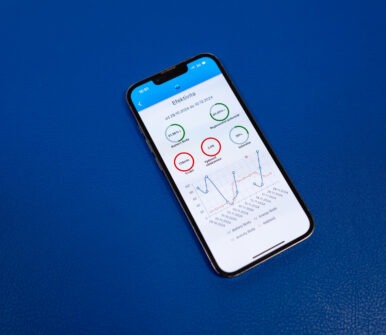 Mobilní telefon položený na modrém podkladu zobrazující statistiky a analýzu efektivity terapie.