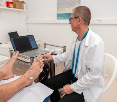 Lékař provádí měření nervové aktivity na chodidle pacienta pomocí elektrod.